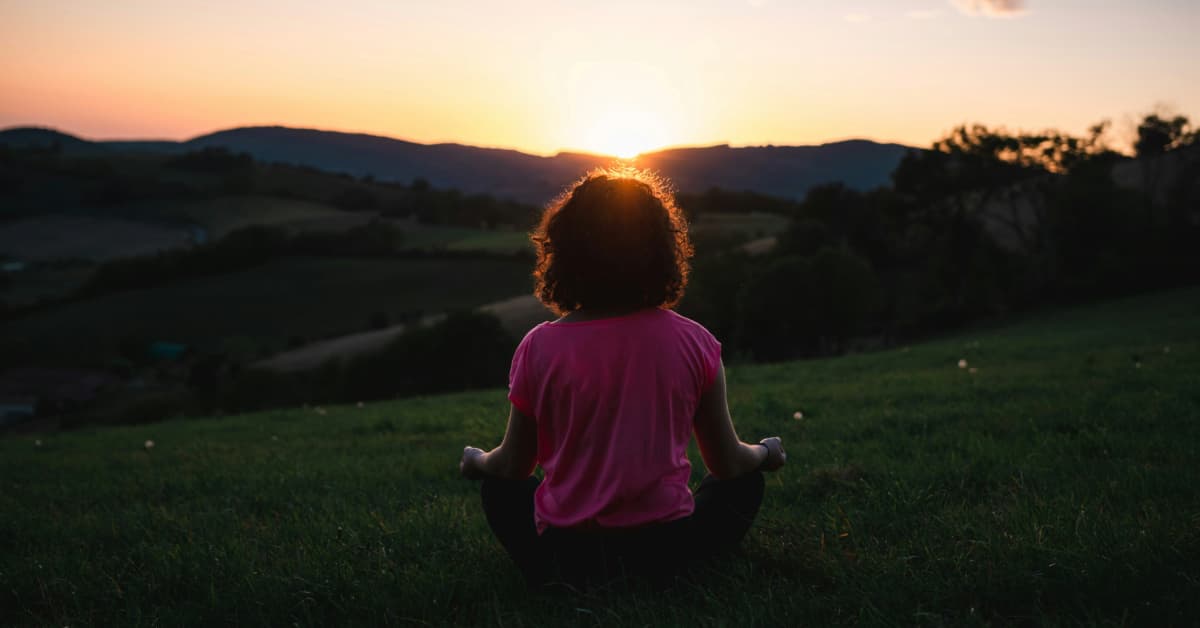 woman meditating in front of sunset